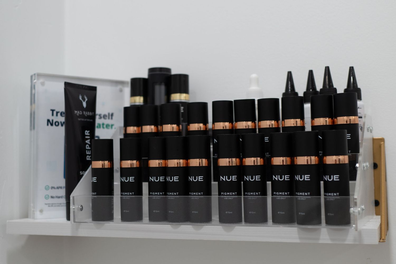 Row of professional hair color products arranged on white shelf display.