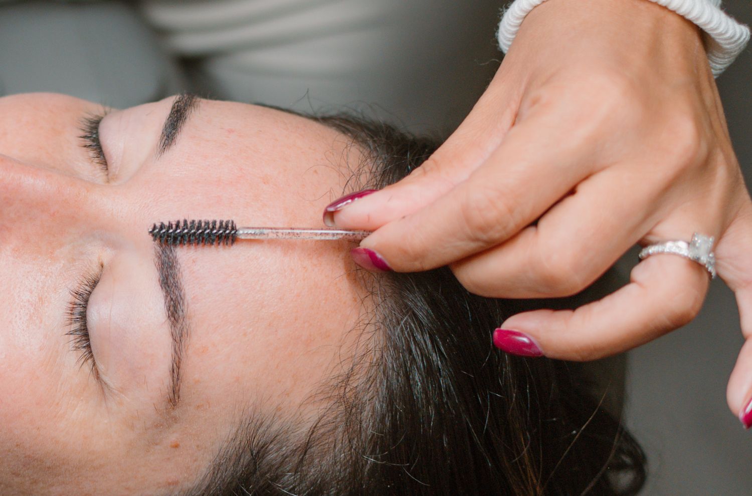 Detailed view of eyebrow grooming using a professional brush tool.