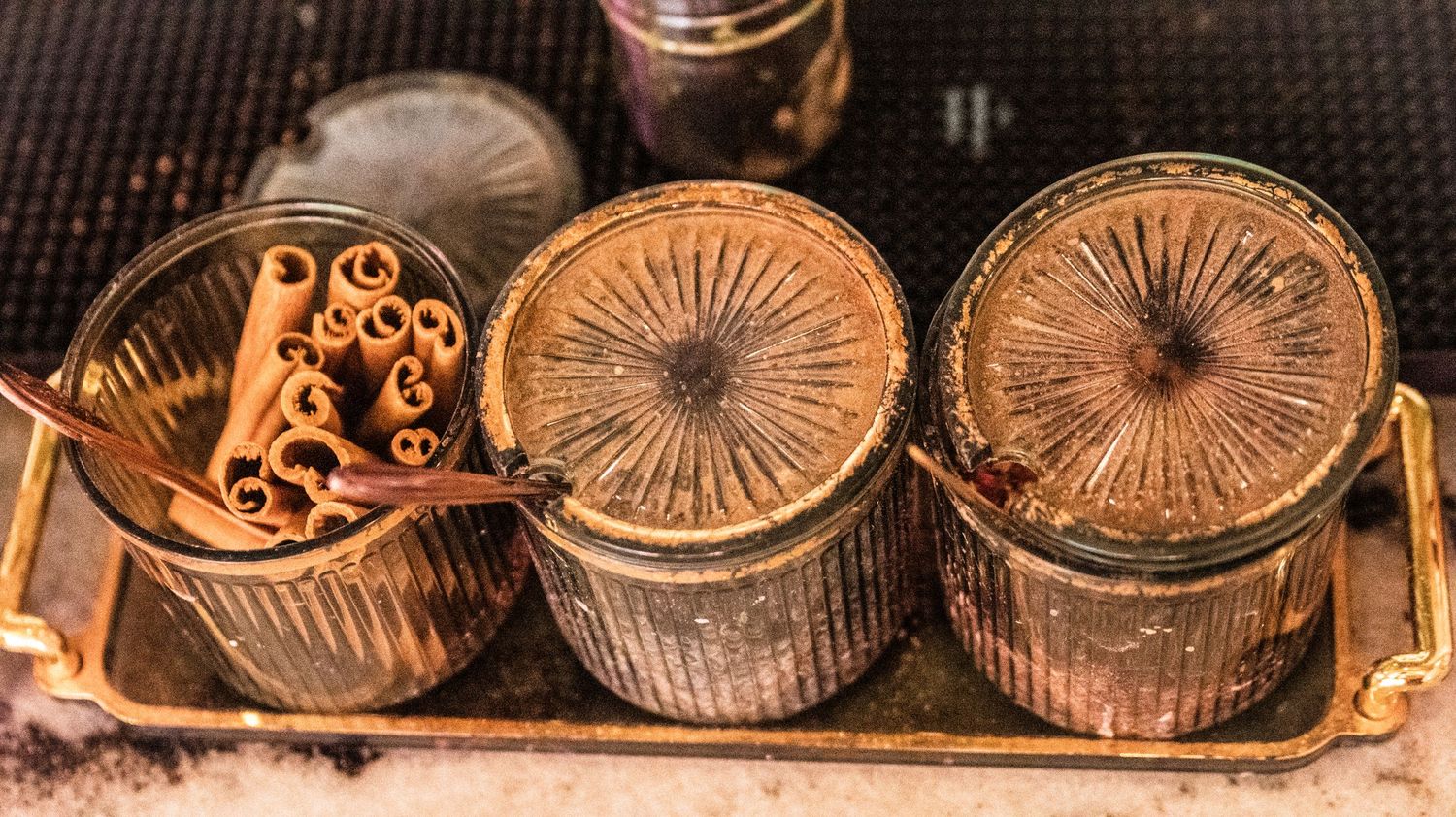 Vintage style glass containers with decorative lids arranged on a metallic tray.