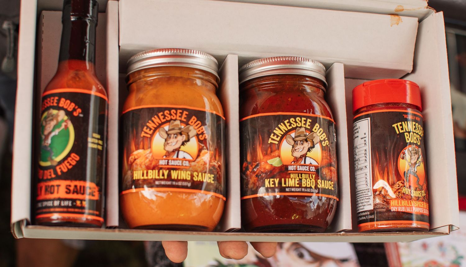 Collection of hot sauce jars and bottles with spicy sauce branding on shelf.