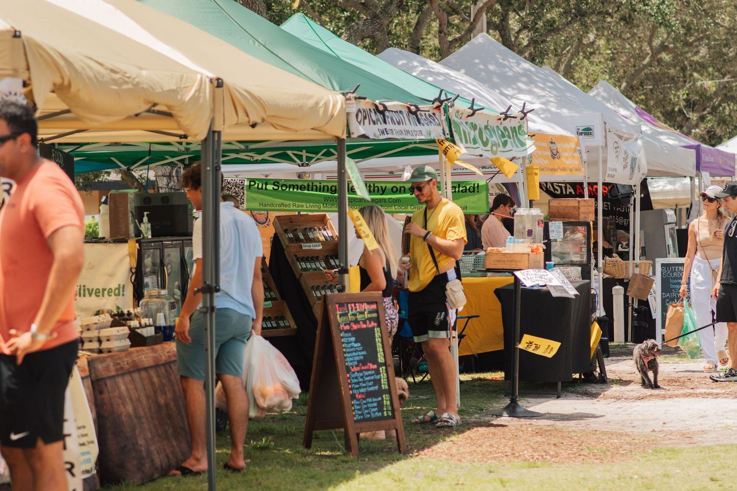 Outdoor market stalls with colorful canopies selling local goods on a sunny day.