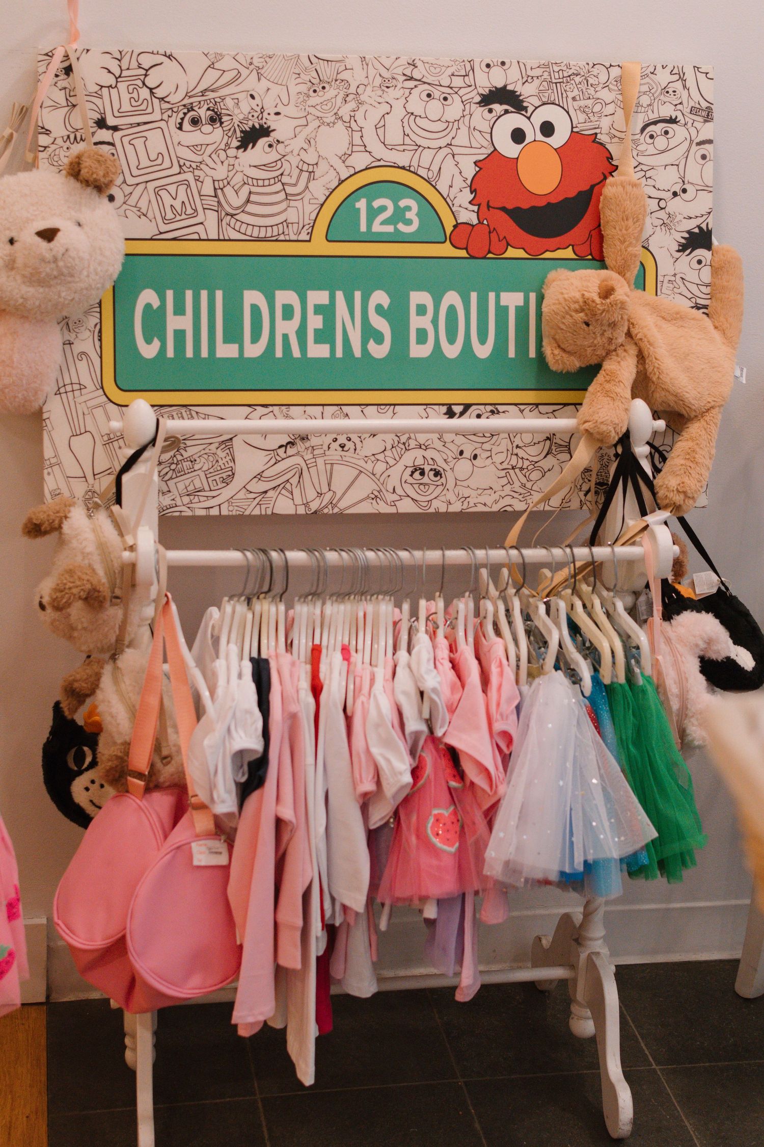 Children's clothing boutique display with Sesame Street theme and stuffed animals.