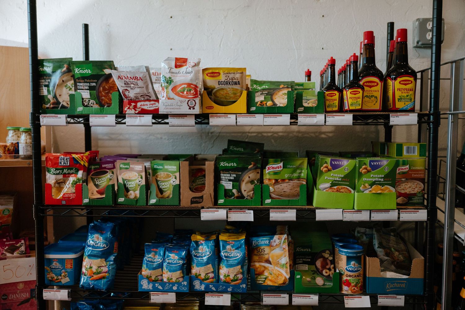Metal storage shelves stocked with various food packages and condiment bottles.