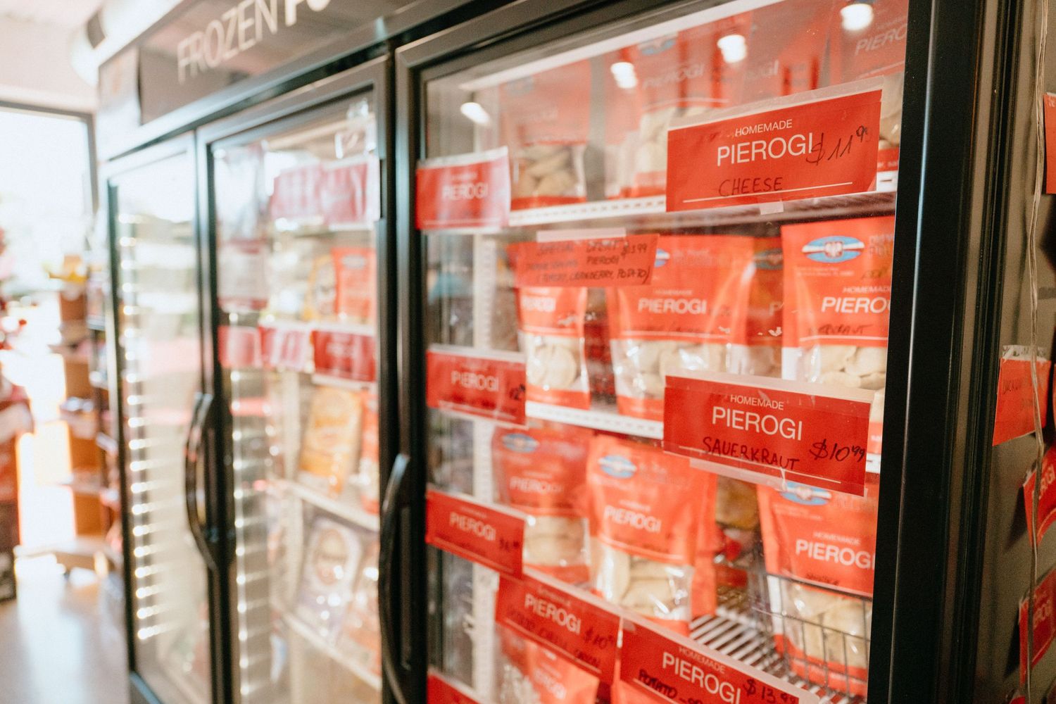 Frozen food section with red Pierogi packages visible through glass freezer doors.