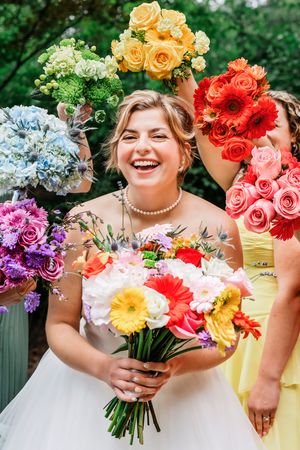 A joyful celebration surrounded by colorful bouquets of roses, hydrangeas, and gerbera daisies in a garden setting.