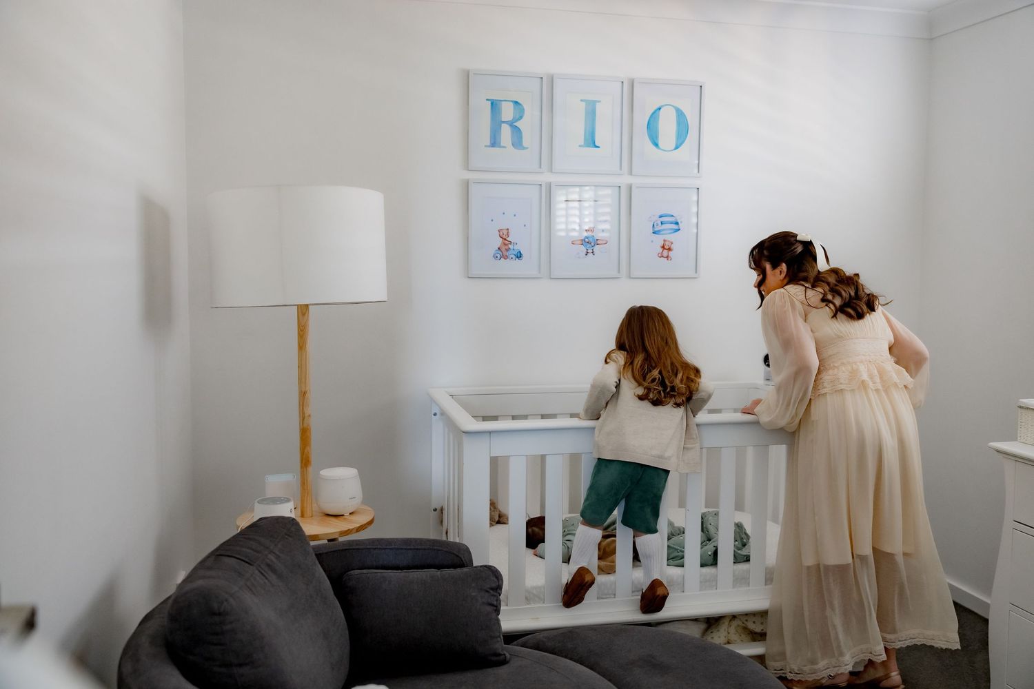 A nursery room with white walls featuring 'RIO' artwork and a white crib.