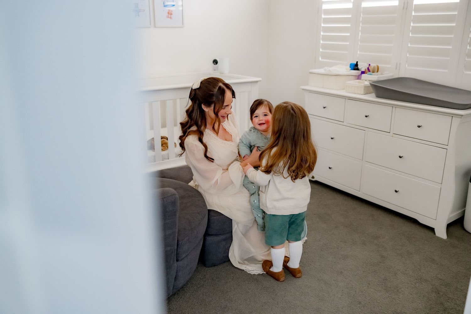 A joyful interaction in a modern white nursery with gray furniture.