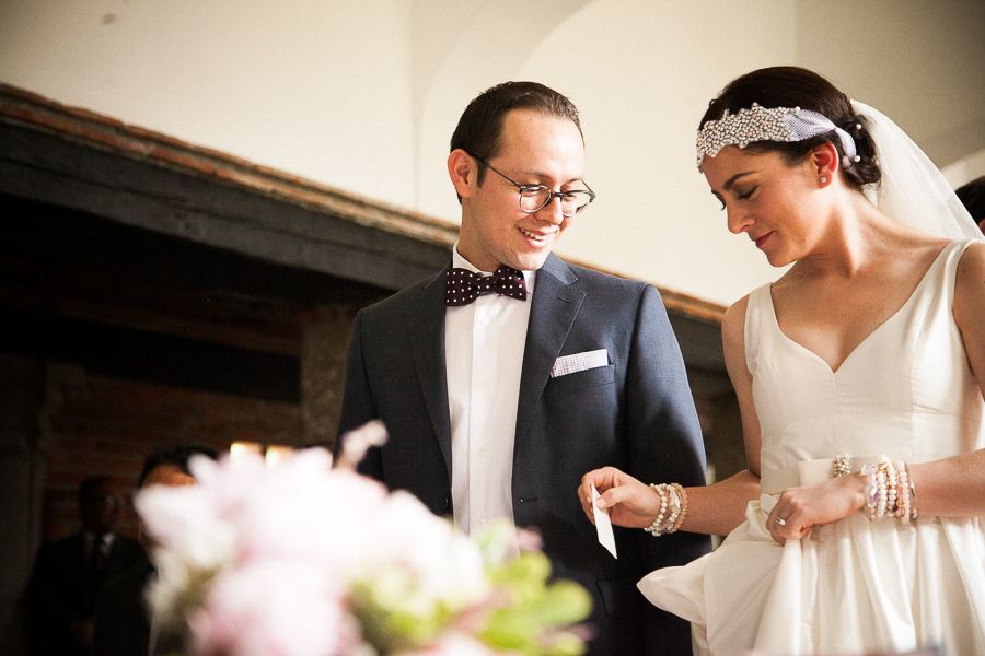 Bride and groom exchanging rings during an intimate wedding ceremony with floral decorations nearby.