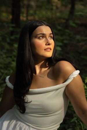 A dreamy portrait in a forest setting featuring an elegant white off-shoulder dress.