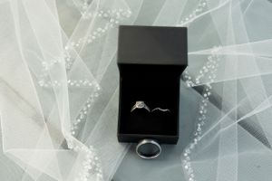 Wedding rings displayed in a black box on ethereal white tulle fabric.