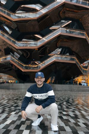 Person in Yankees cap posing at The Vessel structure in New York City.