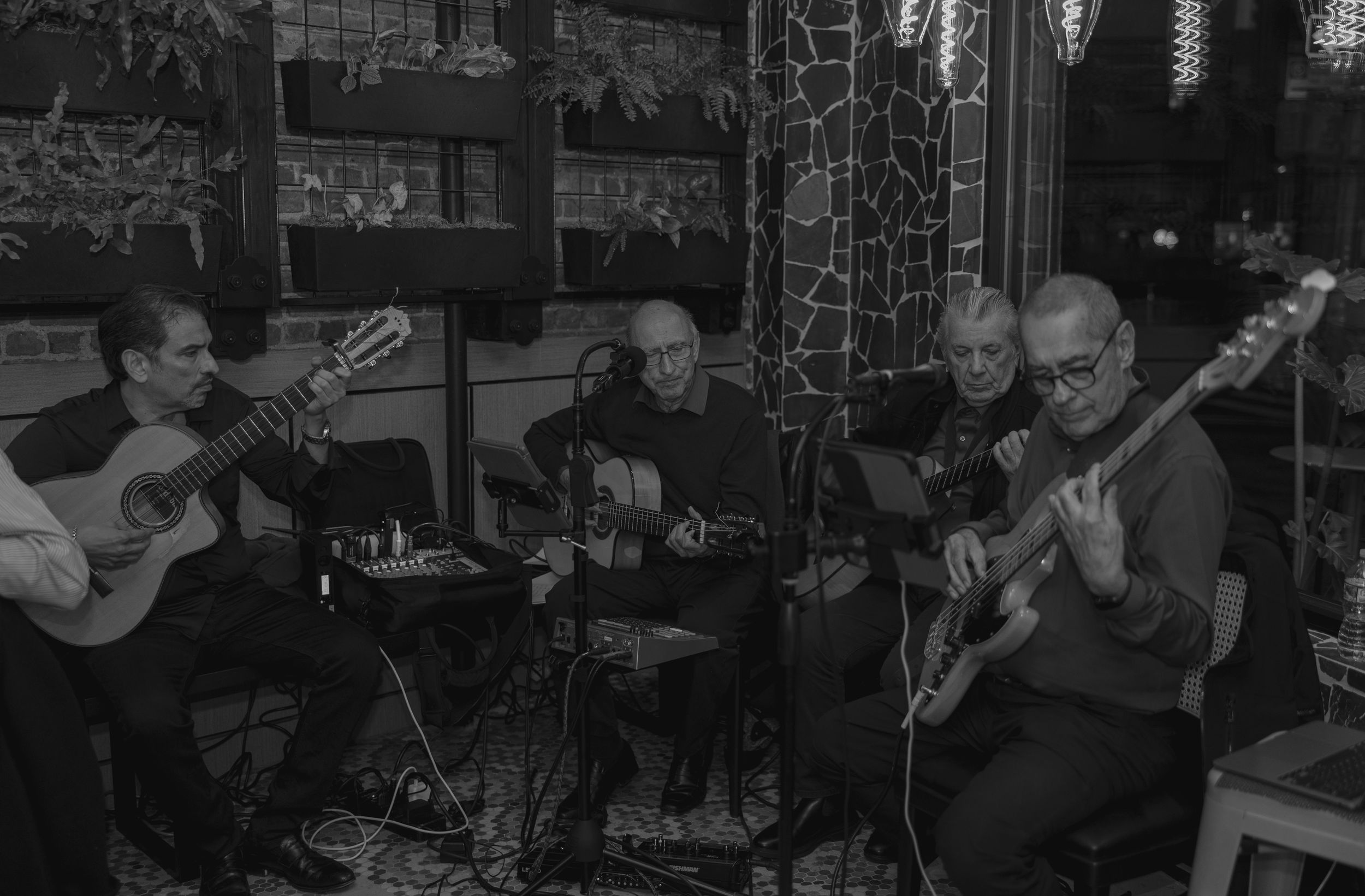 Musicians perform on acoustic guitars during an intimate live music performance in a dimly lit venue.