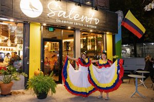 A storefront with Colombian flags and decorative elements illuminated at night.
