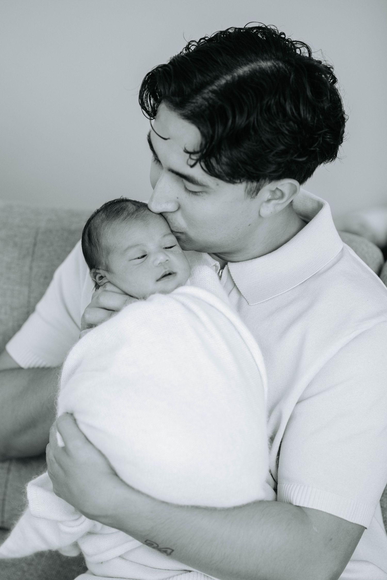 Black and white portrait of tender moment between parent and newborn.