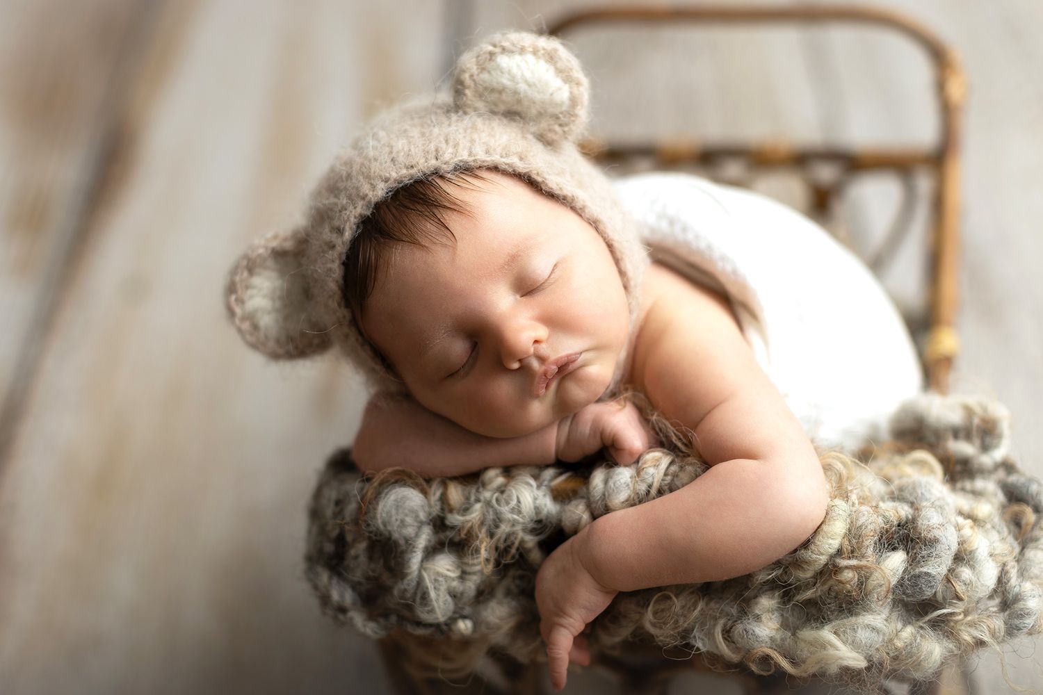 Newborn baby in a cute little pose in a basket.