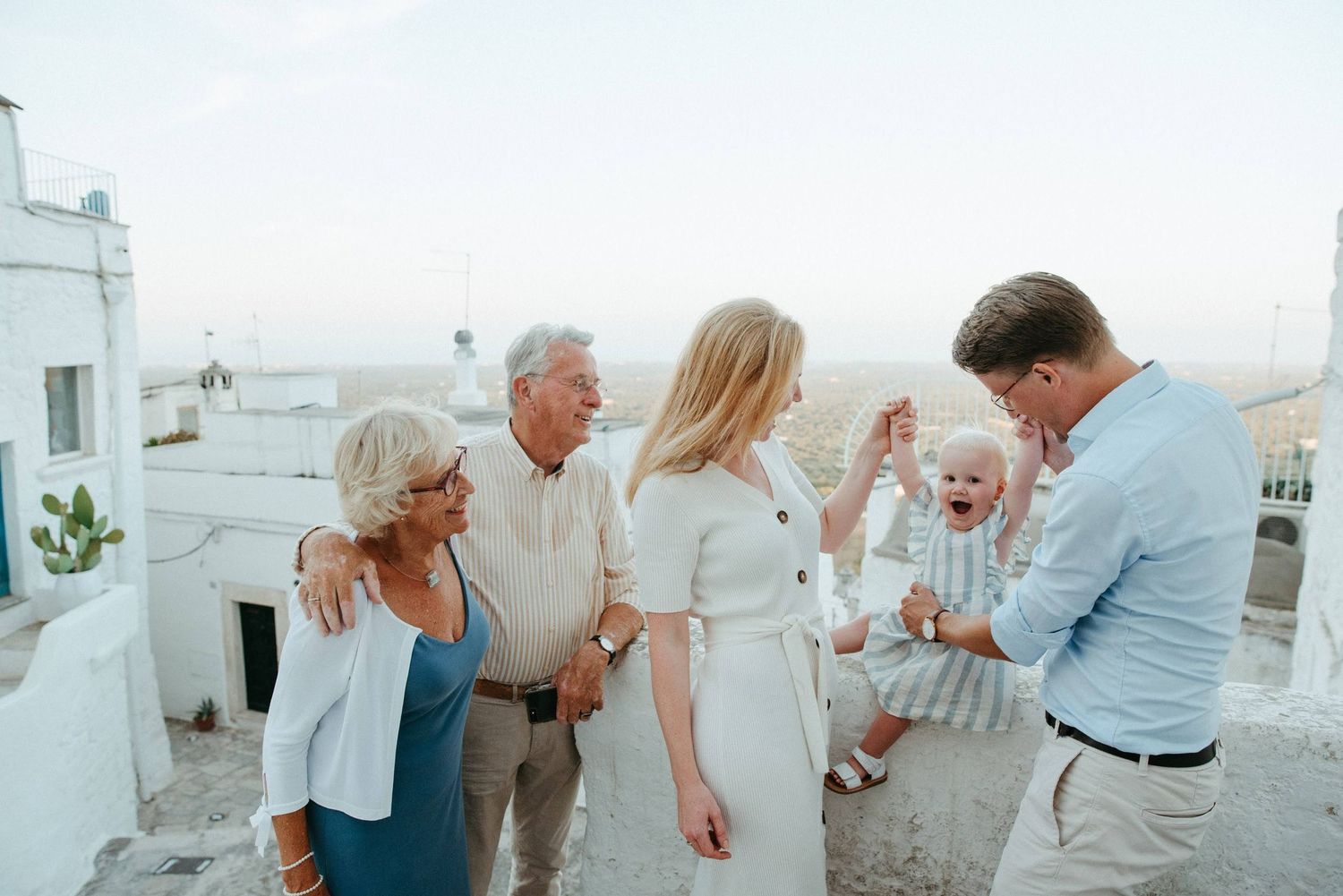 People dancing and celebrating in a bright outdoor setting with white buildings.