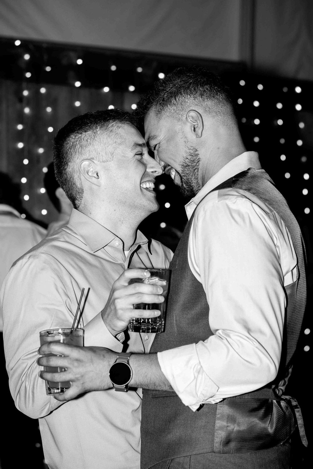 Black and white sequence of two people in white shirts embracing and sharing a drink at a party with twinkling lights.