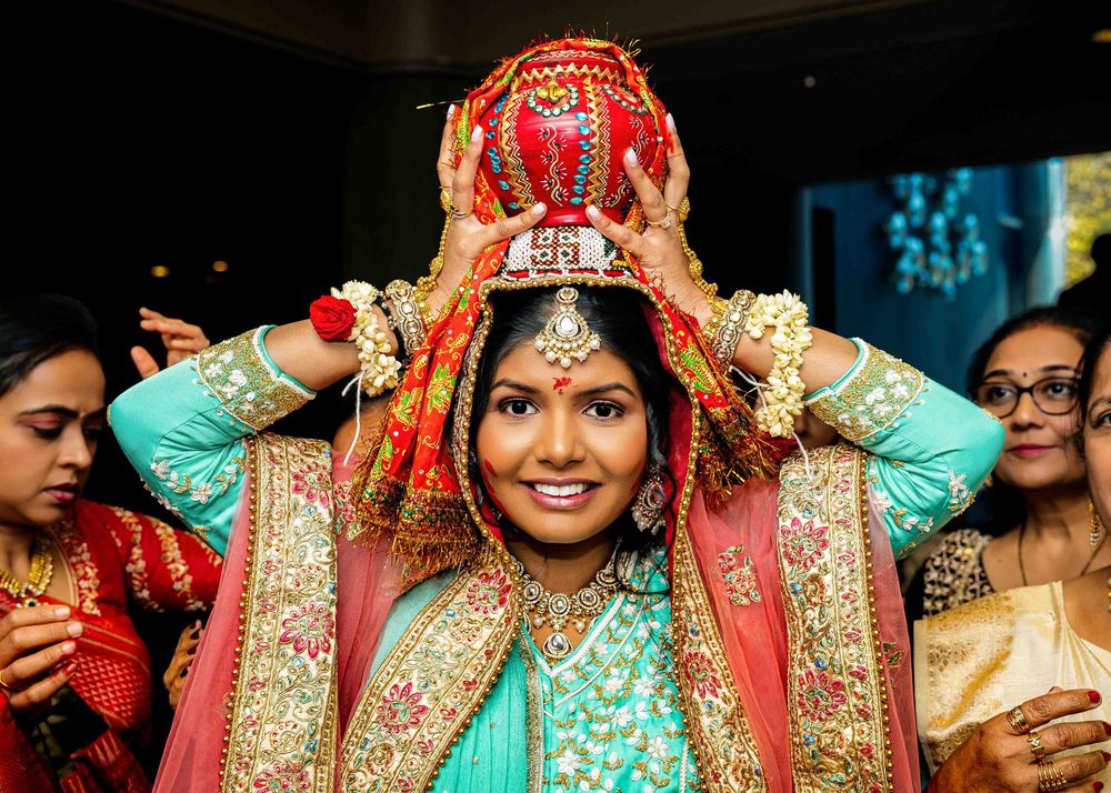 A bride in traditional South Asian wedding attire with ornate jewelry and colorful red and turquoise garments during a ceremony.