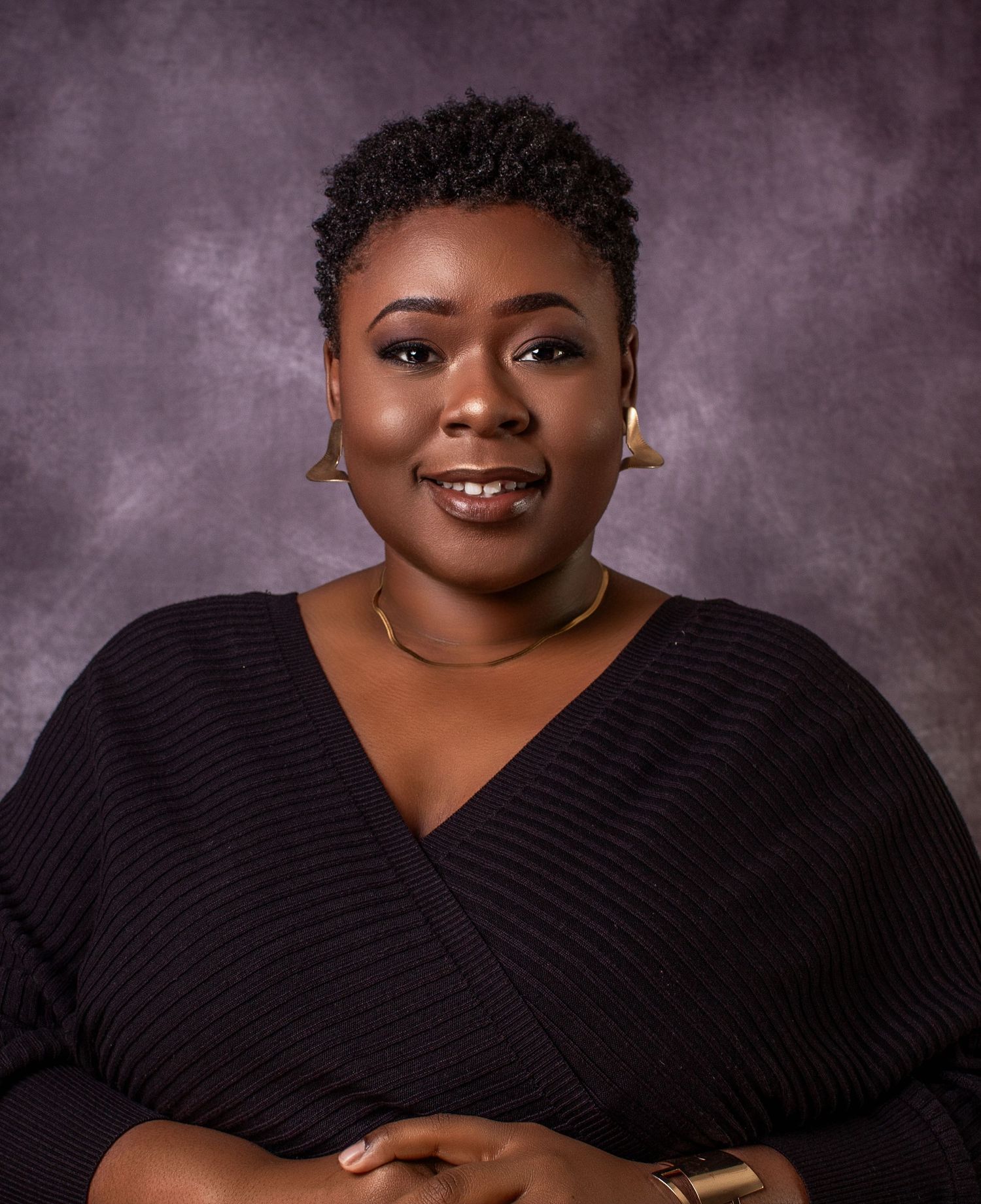 Studio portrait series featuring someone in a black ribbed sweater against a gray textured backdrop. Headshot