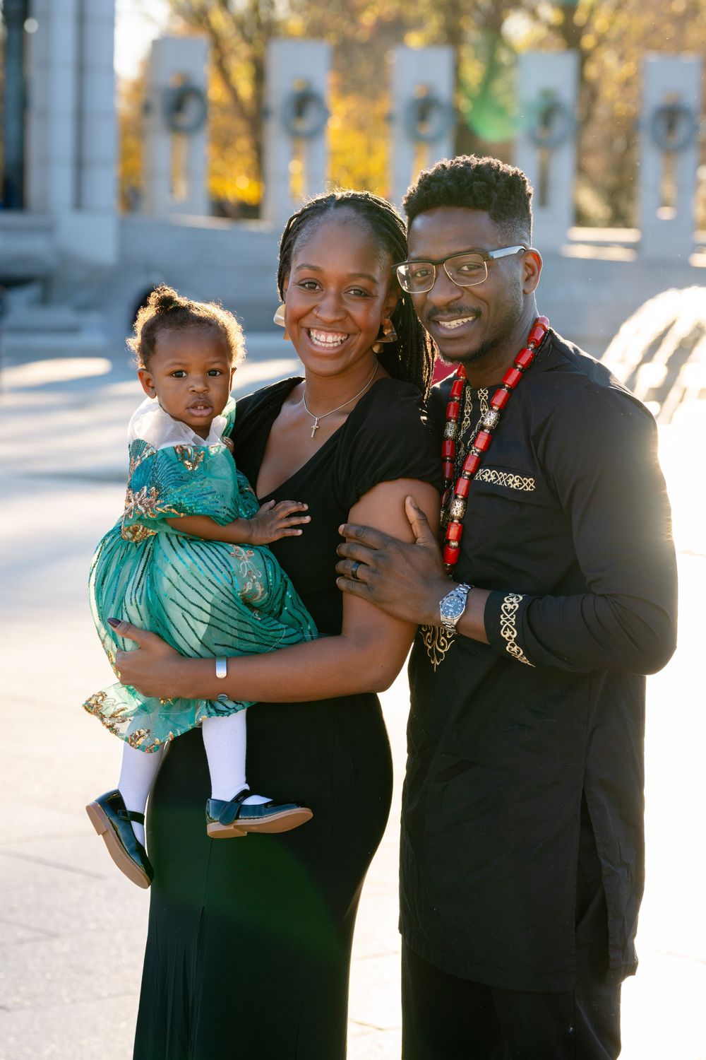 A family wearing black outfits poses together outdoors on a sunny day.