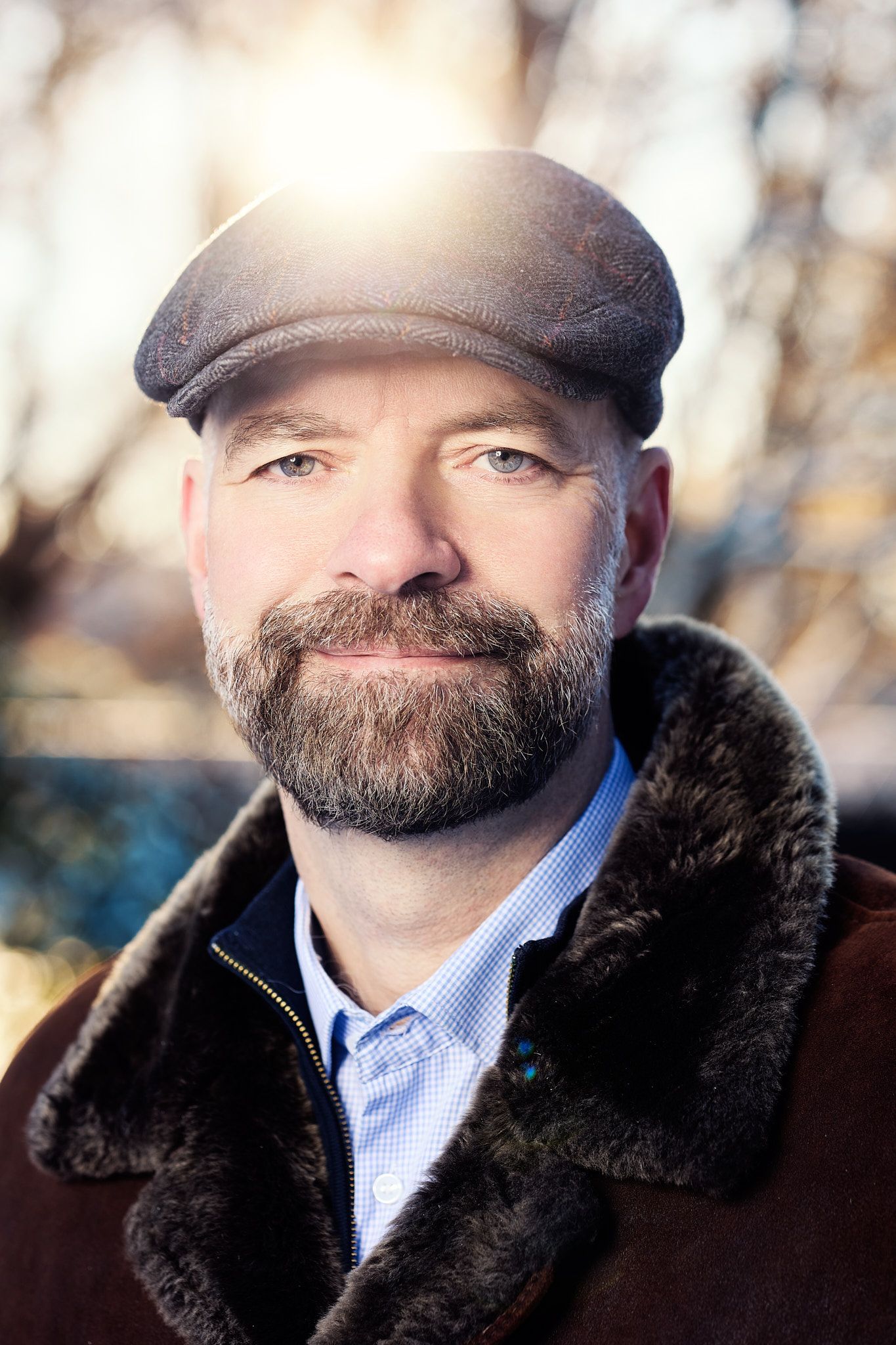 Portrait series of a person wearing a brown winter coat with fur collar and baseball cap against a blurred background.
