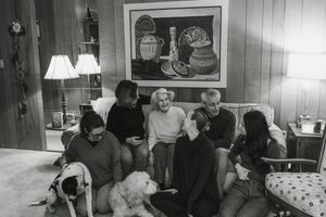 A series of black and white photos showing people gathered in a living room with vintage furniture and decor.