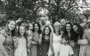 Group photo of extended family gathered outdoors under trees.