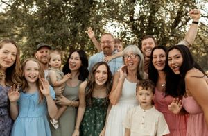 Large family group photo with women and children in colorful dresses.