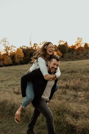Playful piggyback ride in a golden autumn field at sunset.