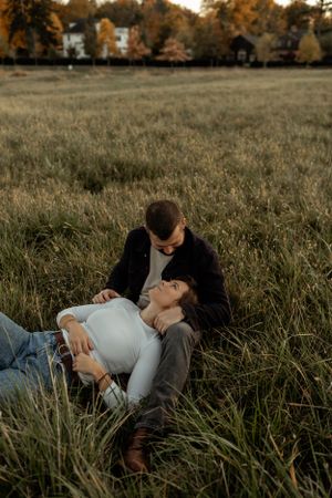 Romantic moment in a field during autumn sunset with houses in background.