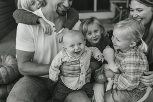 Black and white candid family photo showing joyful laughter and connection.
