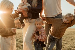 Family gathered together on a hilltop during golden hour sunset.