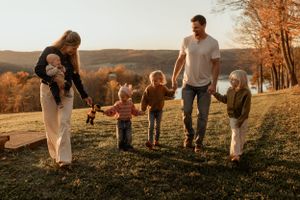 Family walking together on an autumn hillside path against a setting sun.