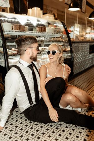 A stylish couple sitting and laughing together at a retro diner counter.