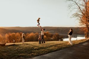 People playing acrobatics on a grassy hillside during sunset with scenic mountain views.