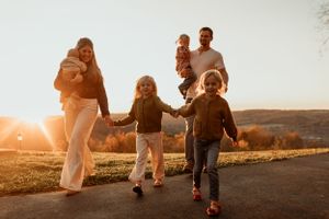 Family walking together on a path at sunset with rolling hills in the background.