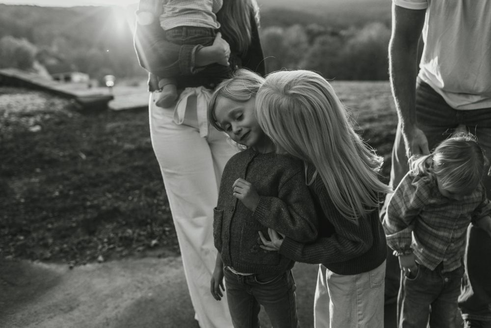 Black and white candid photo of family members hugging outdoors.