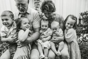A heartwarming family portrait outdoors with children and grandparents in black and white.