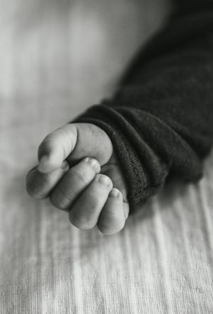Close-up black and white photograph of tiny baby toes on wooden surface.