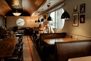 Interior of a cozy restaurant with wooden tables and black pendant lights.