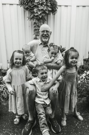 A cheerful family gathering in a garden with white fence and climbing vines.