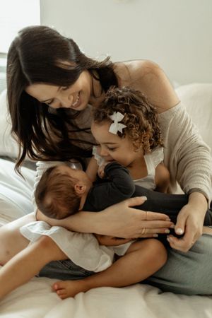 Intimate family moment shared on bed as they cuddle together in soft natural light.
