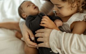 Close-up shot of siblings sharing tender moment together on white bedding.