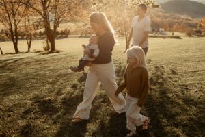 Family walking together in golden sunset light through an autumn field.