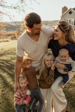 Family enjoying a warm autumn day together on their hillside property with a house in the background.