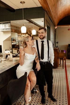 Couple in formal wear sharing a moment in a restaurant with tiled floors.