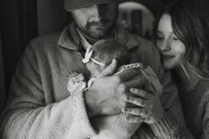 Intimate black and white photos showing a parent bonding with their newborn baby in a series of candid moments.