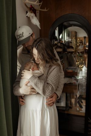 A series of intimate indoor photos showing tender moments between parent and baby in soft, warm lighting.