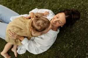 Mother and child sharing peaceful moment while lying on grass outdoors.