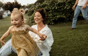 Playful outdoor moment between parent and child in golden sunlight.